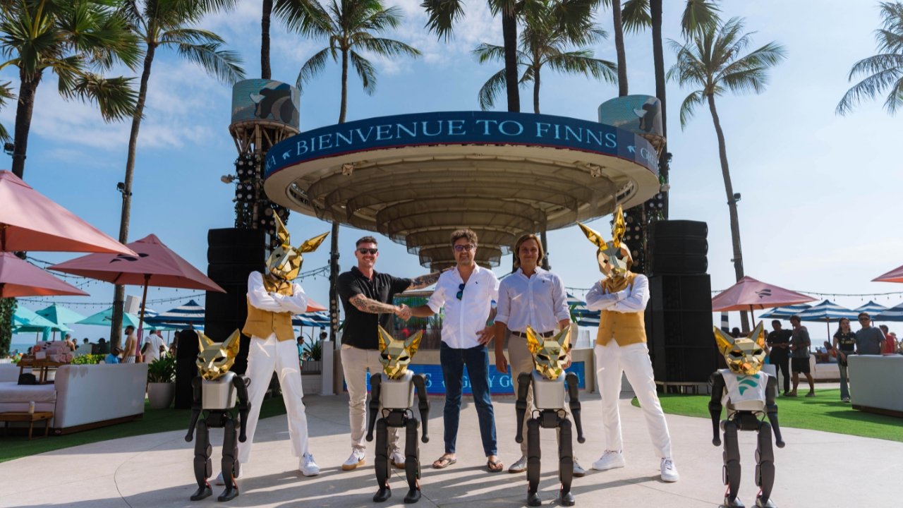 Beau Whittington of FINNS Bali shaking hands with botshift co-founders Alex Ronalds and Bohdan Petryshyn, flanked by the humanoid robot squad in gold masks at Finns Beach Club